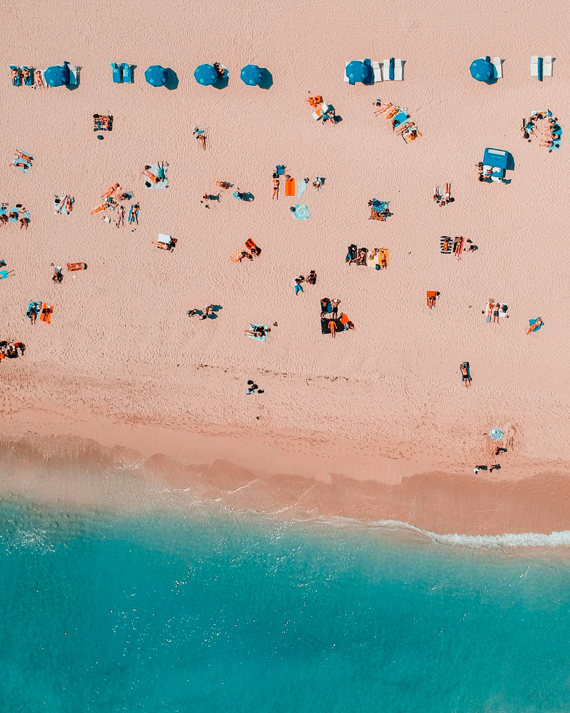 An aerial view of a beach with people and umbrellas.